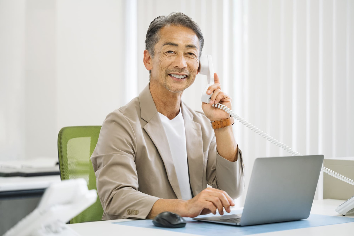 前歯をブリッジ治療した男性が笑顔で電話をしているイメージ