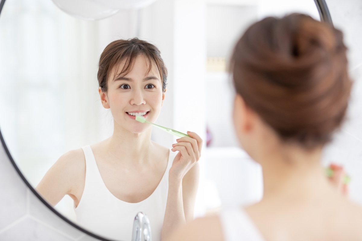 鏡を見ながら丁寧に歯みがきをする女性